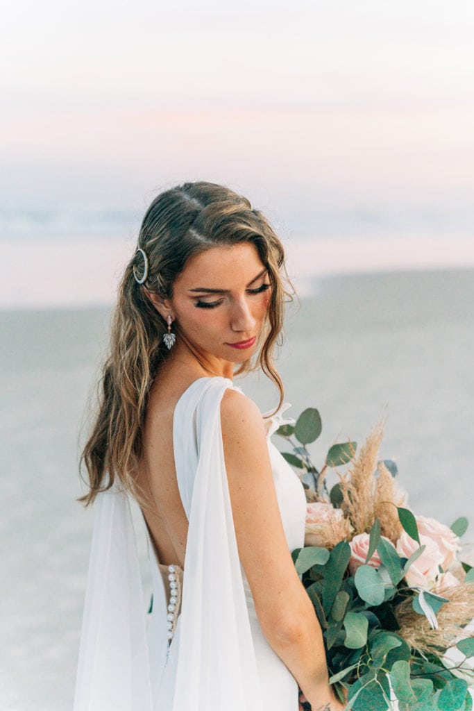 Wedding Photographer, A bride stands before the ocean with her bouquet of flowers