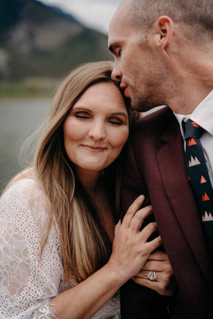 Elopement Photographer, a man kisses his lover on the head as they embrace outdoors