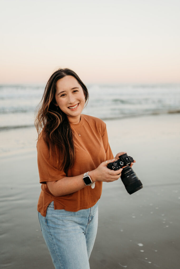 Wedding Photographer, Jessica Lauren, holds her camera as she stands near the seashore at golden hour
