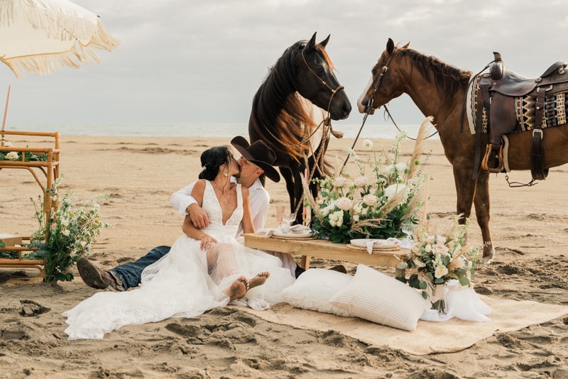 couple enjoys picnic on the beach with horses