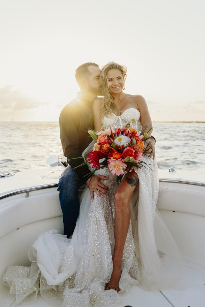 Elopement photographer, couple sits together on boat at sunrise