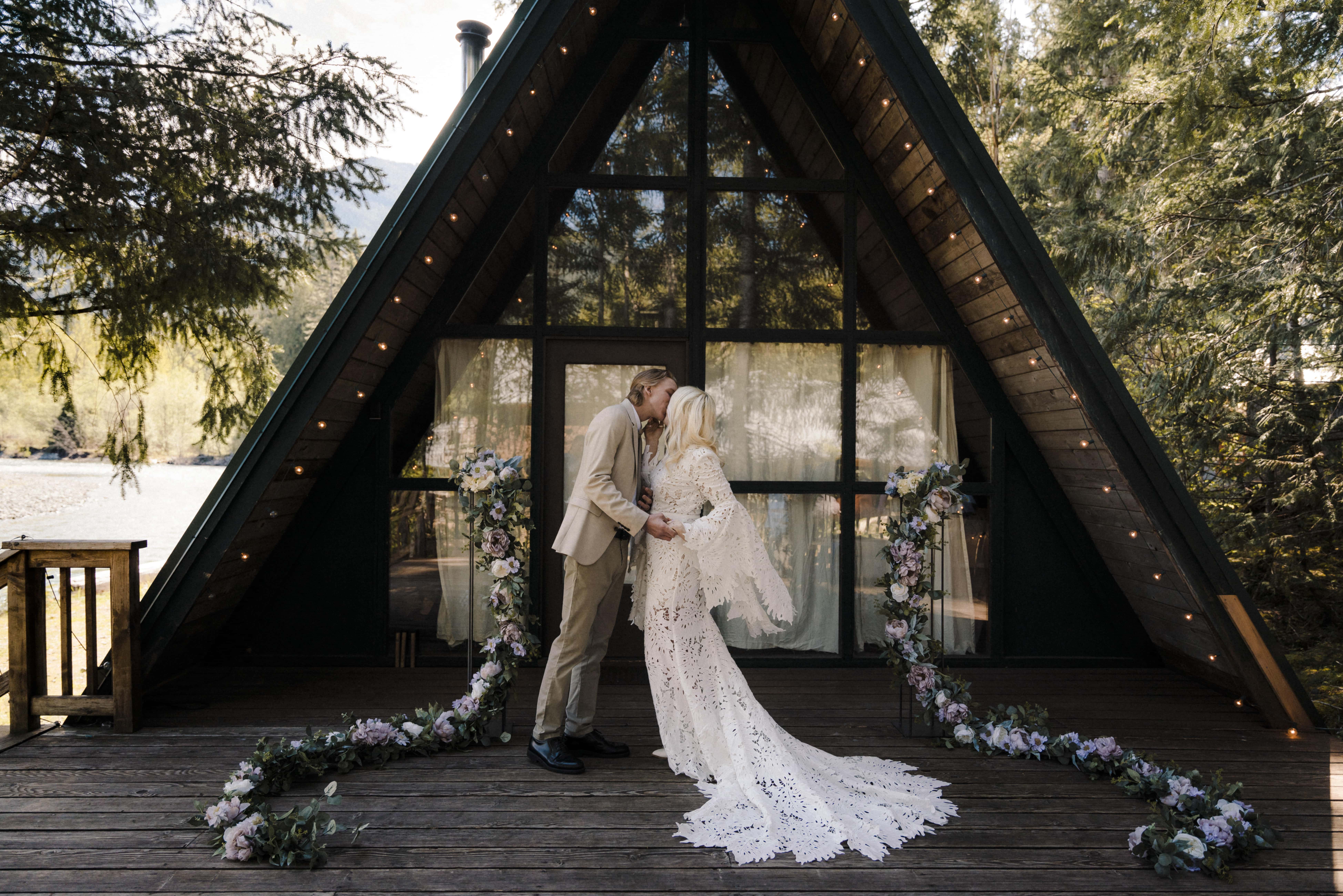 bride and groom kiss in front of mountain cabin in washington
