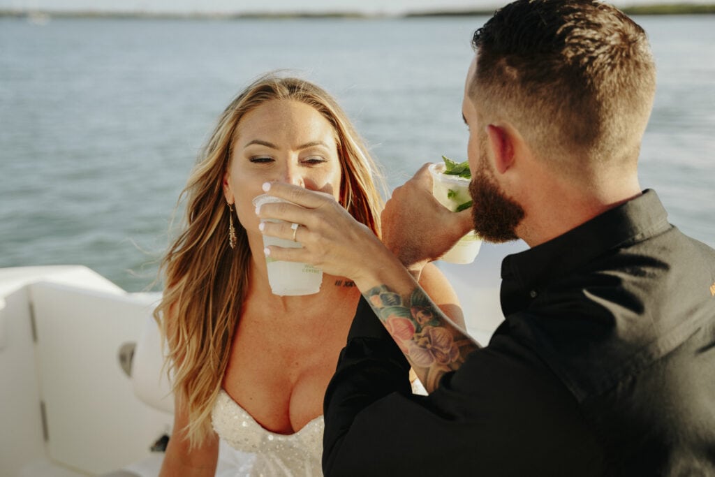 bride and groom share mojitos on a boat