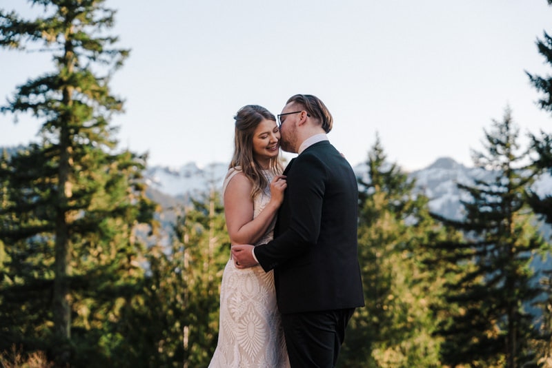 bride and groom embrace in front of mountain range